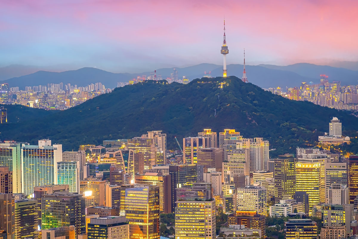 city surrounded by hillsides under a pink sky